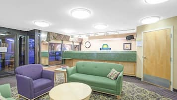 A lobby with a reception desk, a green sofa, a purple armchair, and a small table.