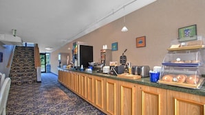 A hotel reception area with a counter, coffee machine, and a display of pastries. - Days Inn by Wyndham Perryville (Perryville)