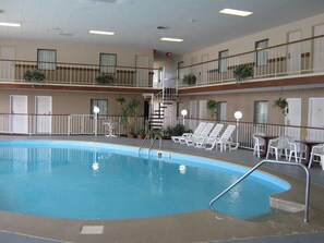 Une piscine intérieure à plusieurs niveaux, offrant une vue dégagée sur l’ensemble de l’espace piscine, dotée de nombreux fauteuils de relaxation et d’un escalier menant à un niveau supérieur.