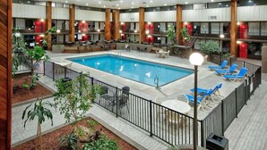 Una piscina interior con sillones de descanso, una lámpara de bronceado y vistas al área de la piscina.
