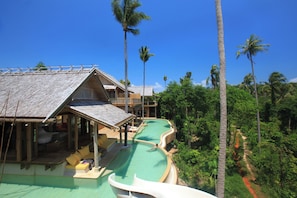 A resort with a swimming pool, lounge area, and tropical vegetation.