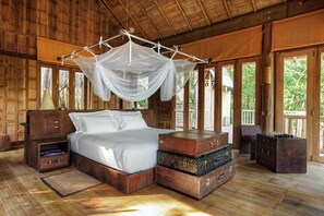 A wooden room with a bed, a nightstand, a bedside table, and a canopy bed.