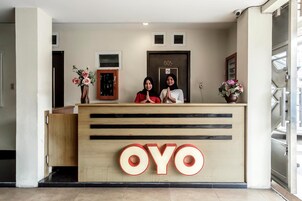Una recepción con un gran logotipo de 'OYO', una puerta con un número y una cámara de seguridad.