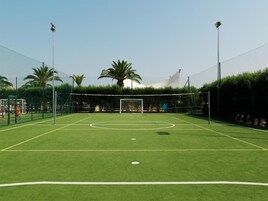 A soccer field with goalposts, a net, and surrounding fencing.