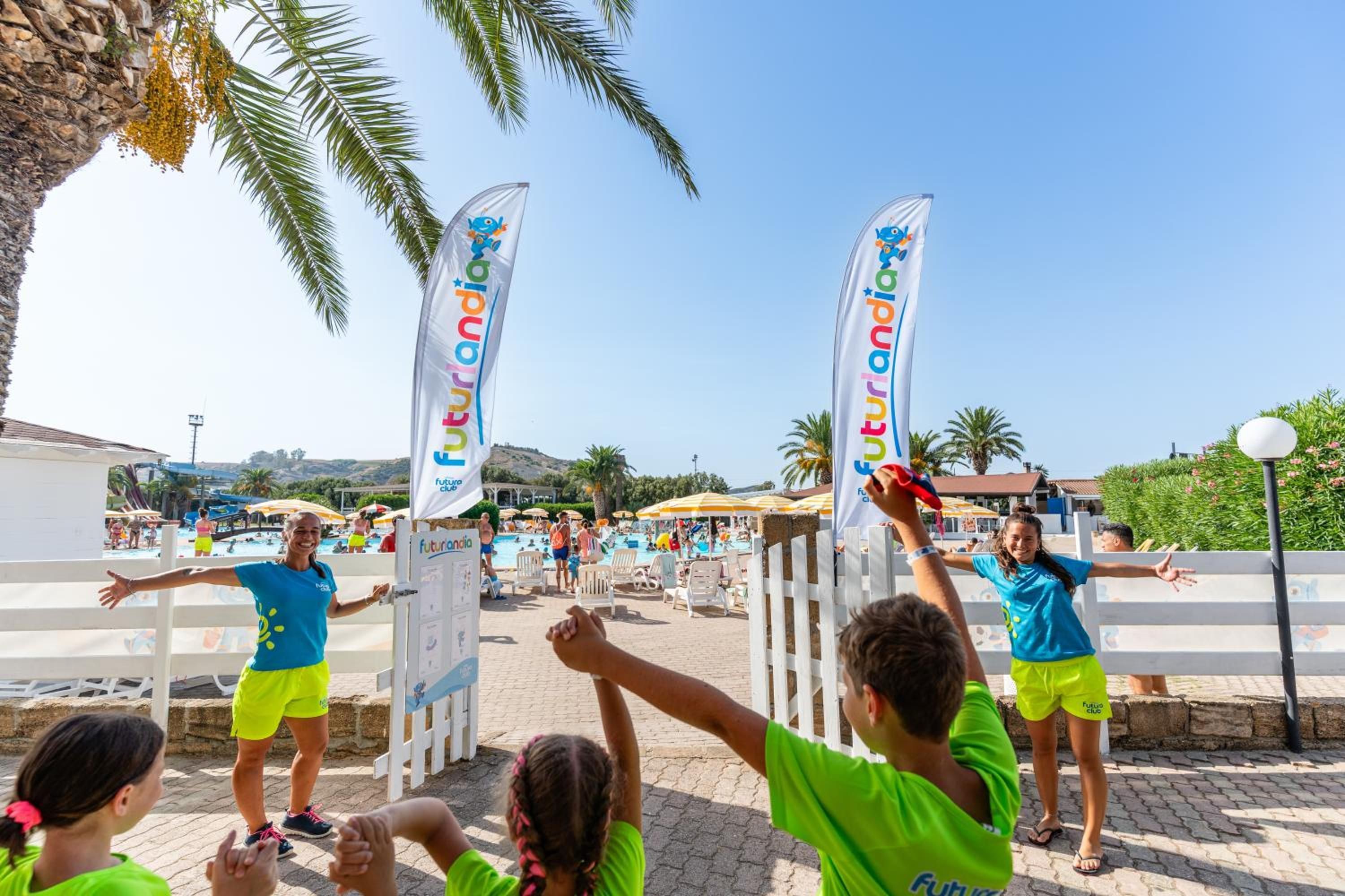 Evento en la playa con pancartas y gente vestida con ropa colorida.