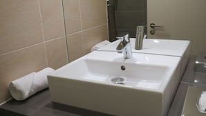 A bathroom with two white sinks, a towel, and a shower area. - Garner Hotel Preston Samlesbury (Preston)