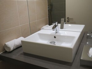 A bathroom with two white sinks, a towel, and a shower area. - Garner Hotel Preston Samlesbury (Preston)