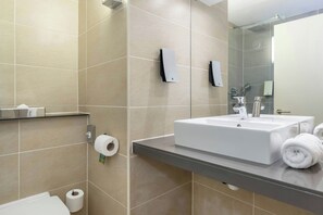 A modern bathroom with a large sink, mirror, and towel rack. - Garner Hotel Preston Samlesbury (Preston)
