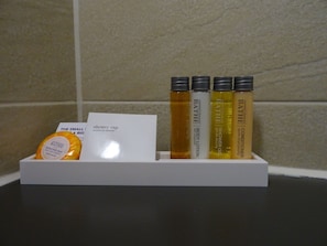 Une étagère de salle de bain contenant des articles de toilette, notamment un bonnet de douche, une lotion pour le corps et un après-shampoing.