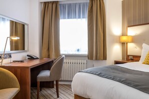 A hotel room with a bed, desk, chair, and a radiator. - Garner Hotel Preston Samlesbury (Preston)