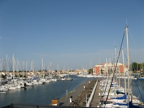 A marina with numerous boats docked along the waterfront, a stone walkway, and buildings in the background. - T2 50M2 BELLE VUE CALME CENTER PORT PARKING SÉCURISE (Agde)