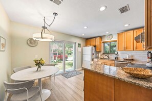 Eine moderne Küche mit Holzausstattung, einer Arbeitsplatte aus Granit und einem Essbereich mit Tisch und Stühlen.