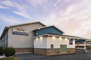 Ett Baymont by Wyndham-hotell med modern design, en parkeringsplats och en klar himmel.