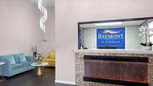 Eine Hotelhalle mit einer Rezeption, einem Kamin, einem blauen Sofa und einem gelben Sessel.