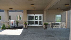 Entrada de um prédio da FedEx Express, com fachada de tijolos, porta de vidro e calçada.