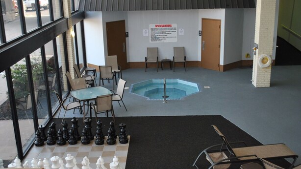 Área de piscina com um tabuleiro de xadrez, cadeiras e um aviso sobre as regras do spa.