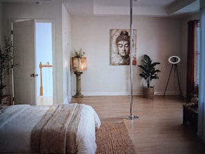A bedroom with a bed, a potted plant, a floor lamp, a painting, and a tripod. - Serene Stay w/ Fireplace & Large Private Backyard (Riverdale)