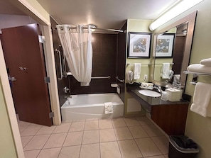Un baño con bañera, ducha, lavamanos, espejo e inodoro.