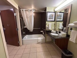Un baño con bañera, ducha, lavamanos, espejo e inodoro.