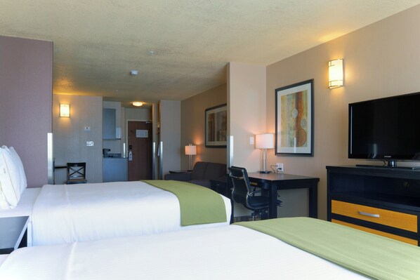 A hotel room with two beds, a desk, a chair, a television, and a painting on the wall.