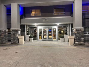Entrada de hotel con puerta giratoria, pilares de piedra y un letrero con el número '12217'.