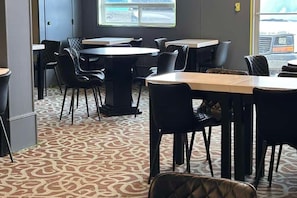 A hotel dining area with round tables and chairs, carpeted flooring, and a window with a view of the street. - Best Western Dawson Creek (Dawson Creek)