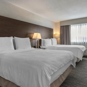 A hotel room with two beds, a nightstand, a lamp, and a window with curtains. - Best Western Dawson Creek (Dawson Creek)