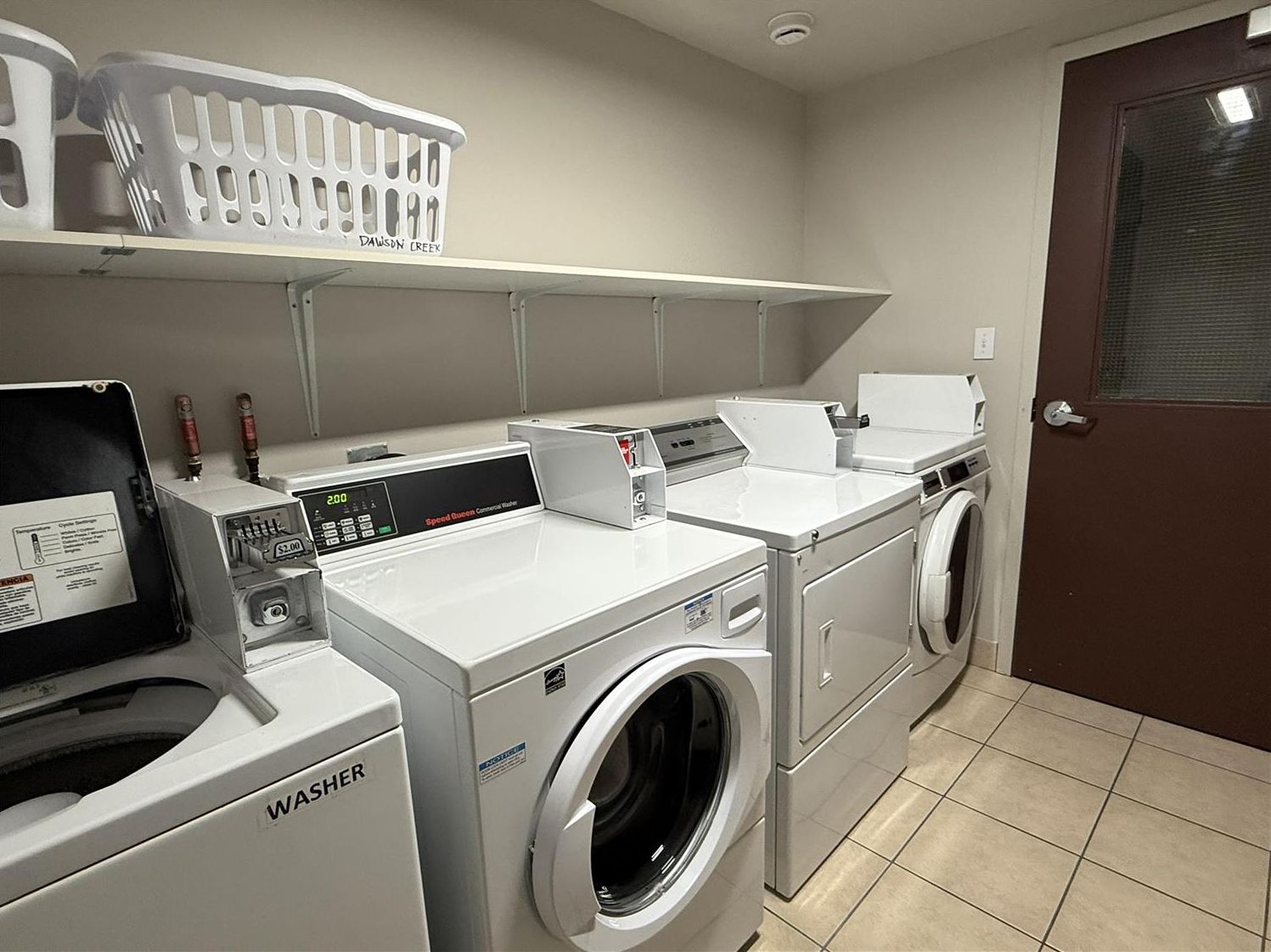 A laundry facility with a front-loading washer, a stacked washer, and a dryer.