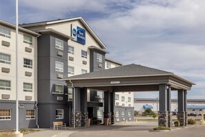 A hotel with a clear entrance, a covered waiting area, and a sign indicating the name 'Best Western.'