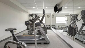 Une salle de sport équipée de machines de cardio, de poids et d’un tapis de course.