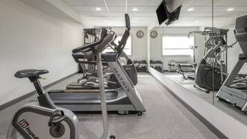 Une salle de sport équipée de machines de cardio, de poids et d’un tapis de course.
