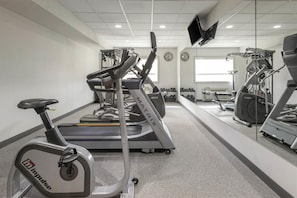 Un gimnasio con equipo de cardio, pesas y cinta de correr.