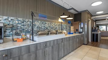 A modern breakfast bar with a marble backsplash, a coffee machine, and a juice dispenser.