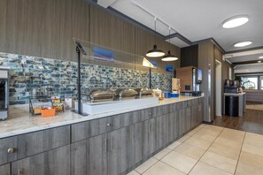 Una barra de desayuno moderna con una salpicadura de mármol, una máquina de café y un dispensador de jugo.