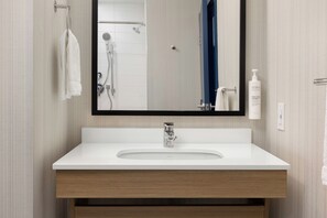 A bathroom with a white sink, a mirror, and a shower. - Spark by Hilton Woodstock (Woodstock)