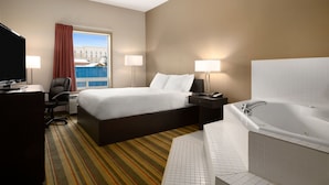 Habitación de hotel con cama, escritorio, televisión y baño con bañera.