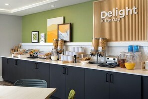 Cozinha moderna com balcão para refeições, máquinas de café e uma placa com a inscrição 'Aproveite o dia'.