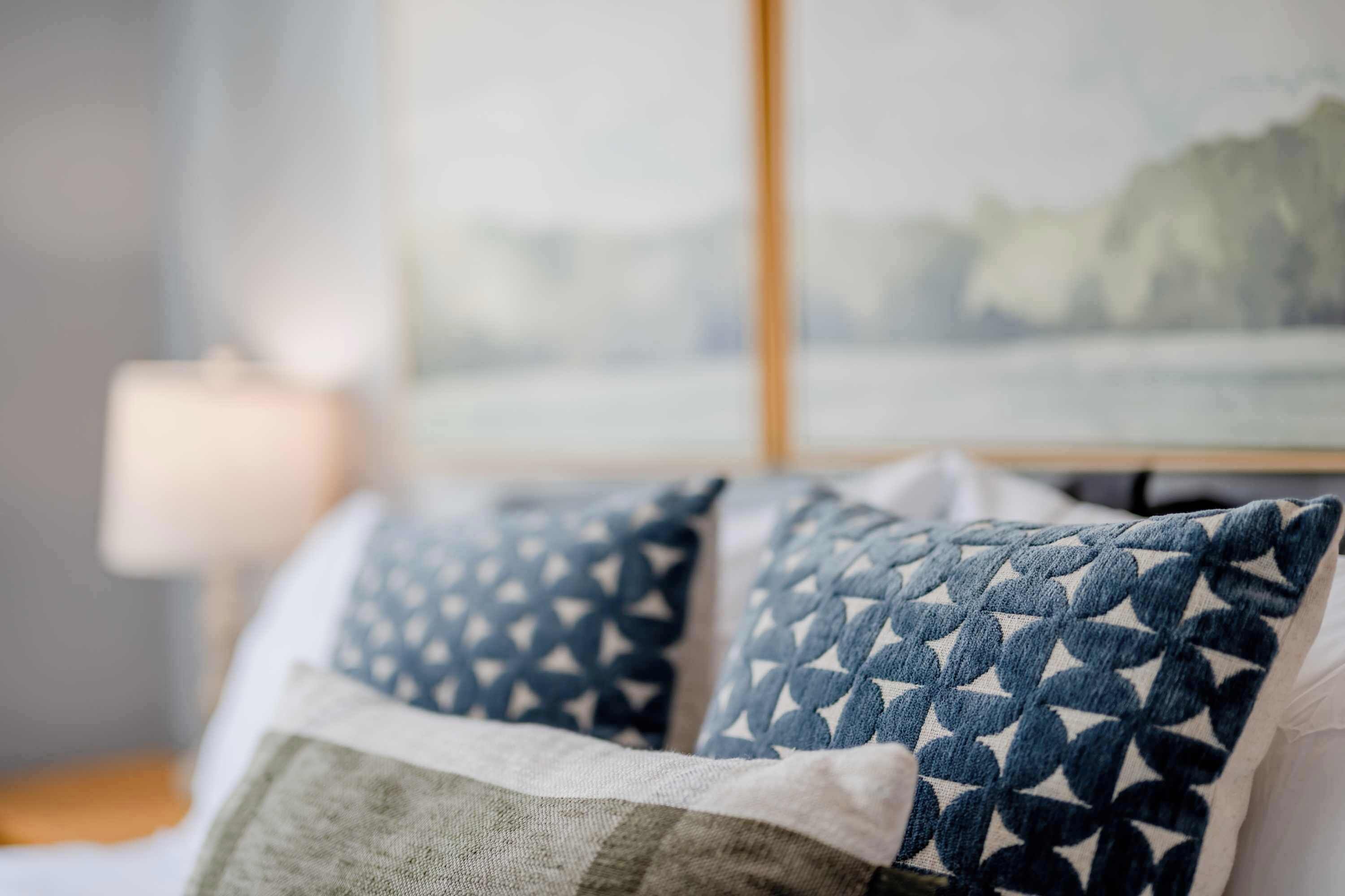 Un lit avec des coussins à motifs et une vue sur un paysage par la fenêtre.