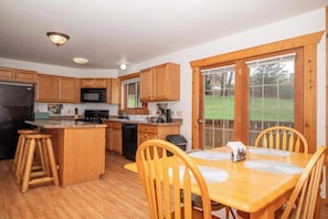 A kitchen with wooden cabinets, a microwave, a stove, and a dining area with a table and chairs.