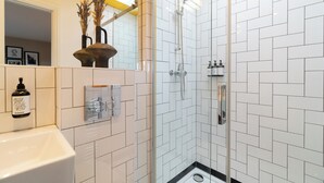 Un bany amb plat de dutxa emblenquinat, un lavabo i un mirall.