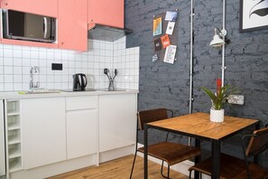 Eine Küche mit weißen Schränken, einer Mikrowelle, einer Kaffeemaschine und einem Tisch mit Stühlen.