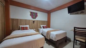 Habitación de hotel con dos camas, cabecero de madera, televisión montada en la pared y una silla.
