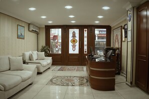A reception area with a desk, a sofa, and a patterned rug. - Nova City Hotel (Istanbul)