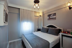 Una habitación de hotel con cama, mesita de noche, lámpara y un cuadro colgado en la pared.