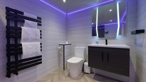 Ein modernes Badezimmer mit integriertem Handtuchhalter, Toilette, Waschbecken und Spiegel.