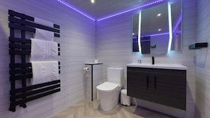 A modern bathroom with a black towel rack, a toilet, a sink, and a mirror. - The Shrubbery Hotel (Ilminster)