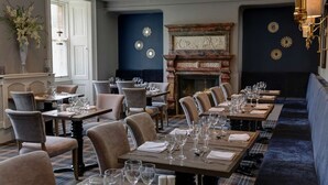 Ein Restaurant mit mehreren Tischen und Stühlen, einem Kamin und dekorativen Wandelementen.