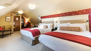 Ein Hotelzimmer mit zwei Betten, einer Couch, einem Schreibtisch und einem Sessel.