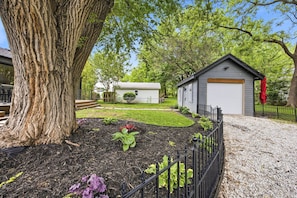 A residential property with a large tree, a garage, and a small shed.