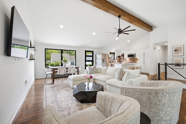 A spacious living area with a large sectional sofa, a coffee table, and a dining area with a table and chairs.